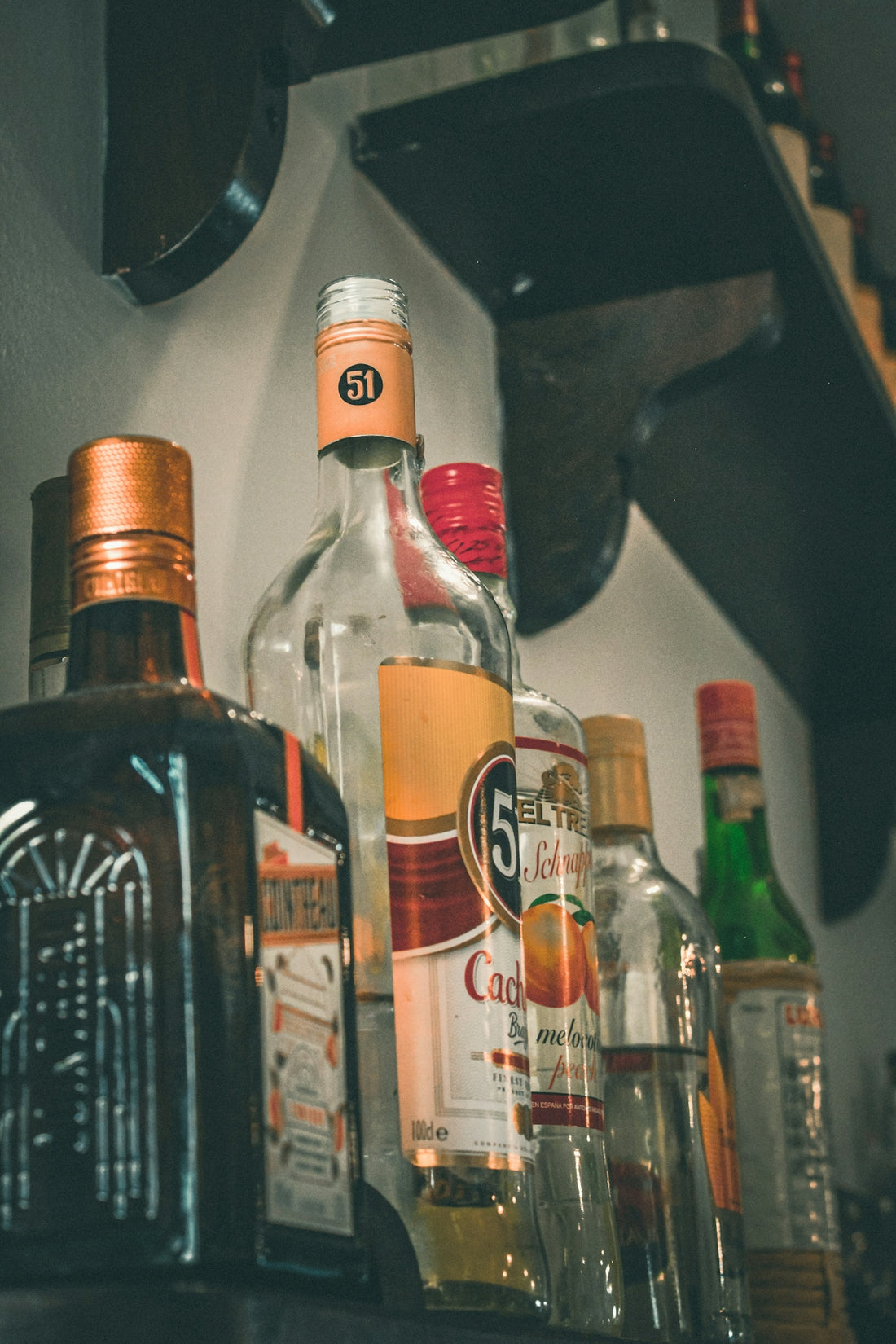 Various bottles of alcohol lined up on a shelf.
